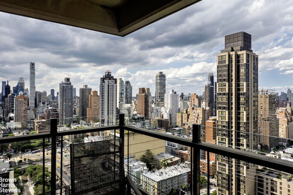 Panoramic view of a cityscape with various skyscrapers and buildings seen from a balcony.