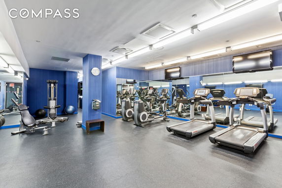 Interior gym area with exercise equipment including treadmills and weight machines.