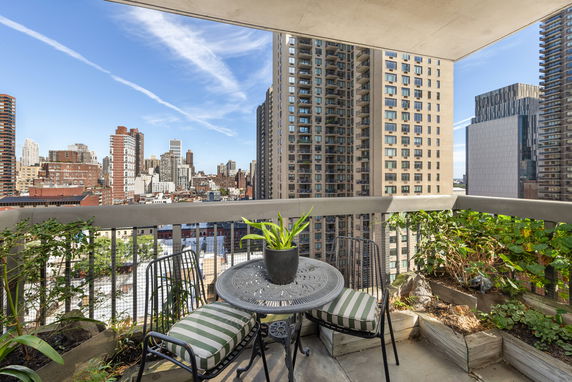 Balcony view with outdoor seating and cityscape.