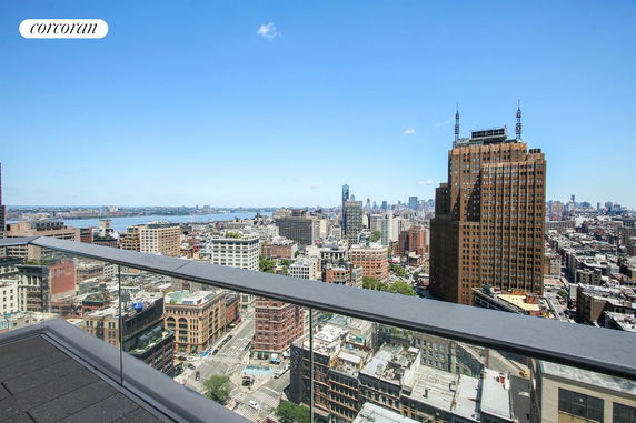 Panoramic view from a high-rise building balcony over a cityscape with skyscrapers and river.