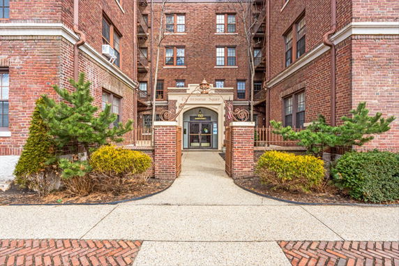 Front view of a multi-story brick apartment building with an entrance gate.