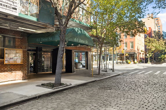 Front entrance of a building with a green canopy and brick exterior on a street corner.