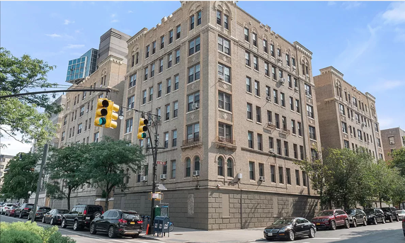 Front view of a multi-story brick apartment building with ornate window details.