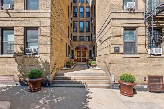 Front view of a multi-story brick building with steps leading to the entrance.