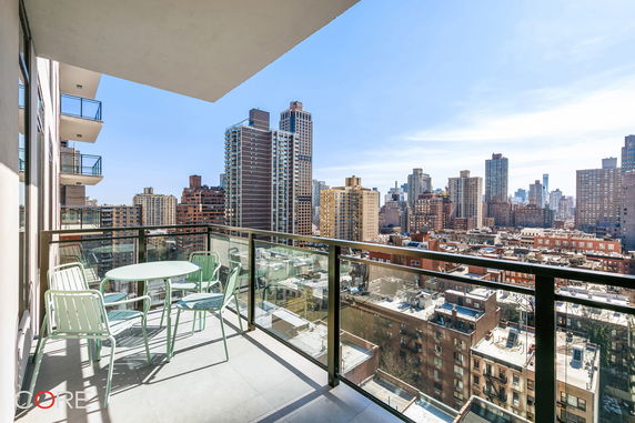 Balcony with glass railing and cityscape view of various tall buildings.