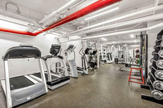 Indoor gym area with exercise equipment including treadmills, weights, and machines.