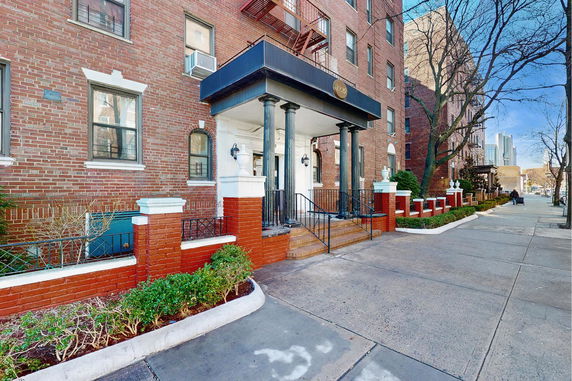 Front view of a brick apartment building with a covered entrance.