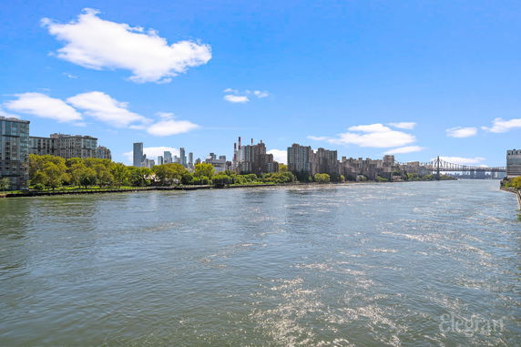 View across the river towards city buildings and a bridge on a clear day.
