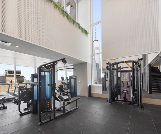 Interior view of a gym area with exercise equipment and large windows.