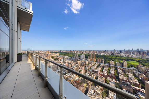 Panoramic view from a high-rise building balcony overlooking a cityscape with expansive greenery.