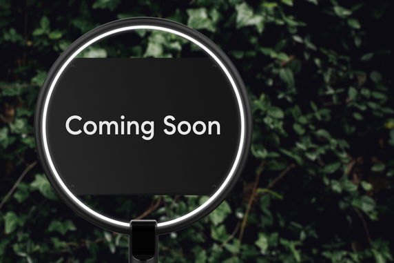 Sign with the words 'Coming Soon' in front of foliage.