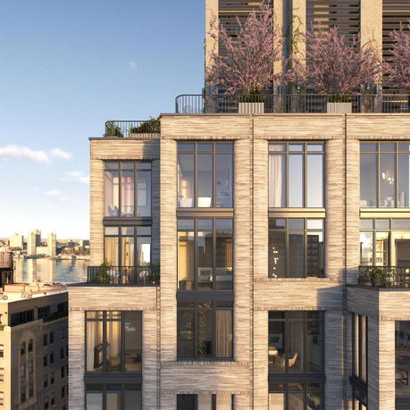 Front view of a multi-story building with large windows and a rooftop garden.