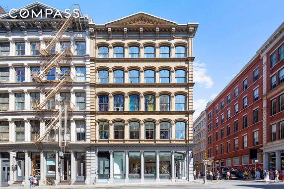 Front view of a multi-story urban building with large windows and a fire escape.