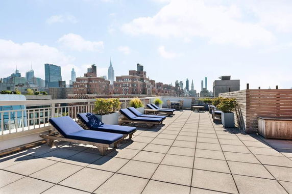 Rooftop area with lounge chairs and a view of the city skyline.