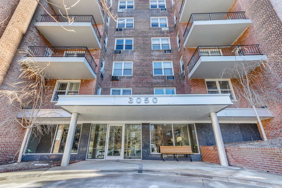 Front view of a multi-story building with balconies and glass entrance.
