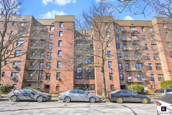 Front view of a multi-story brick apartment building with fire escapes.