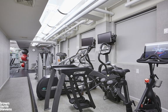 Indoor gym with various exercise equipment and machines.