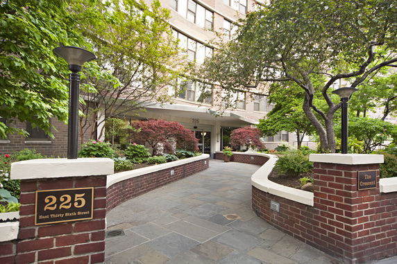Front view of a building entrance with a landscaped path and brick walls.