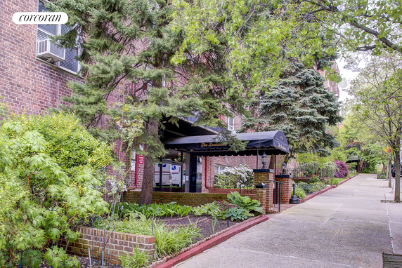 Front view of a brick building with trees and a covered entrance.
