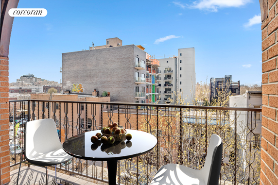 View from a balcony showing surrounding buildings and a table with chairs.