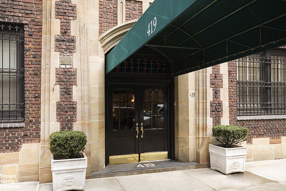 Front view of a building entrance with a green canopy and glass-paneled doors.