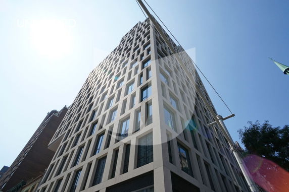 Front view of a tall, modern, multi-story building with a geometric window design.