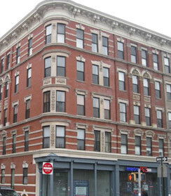 Front view of a multi-story brick building with commercial space on the ground floor.