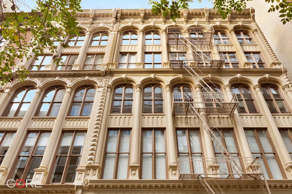 Front view of a multi-story building with large arched windows and an exterior fire escape.