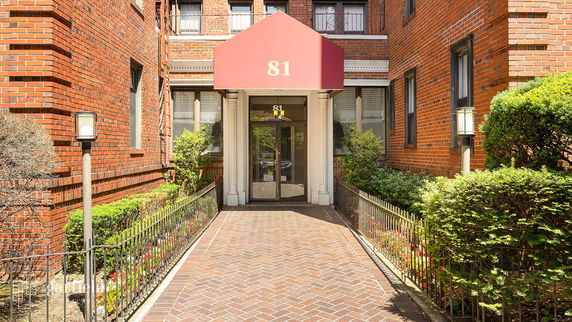 Front view of a brick building entrance with number 81 on the canopy.