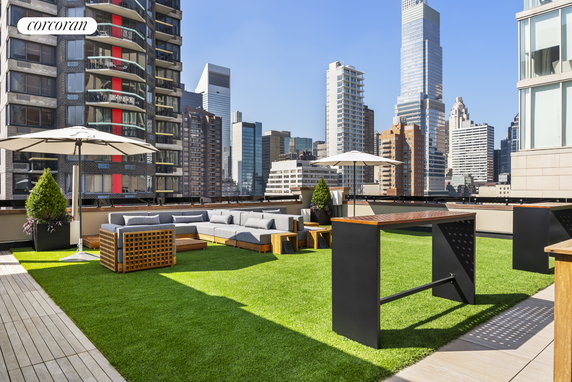 Rooftop area with seating and parasols overlooking city skyscrapers.