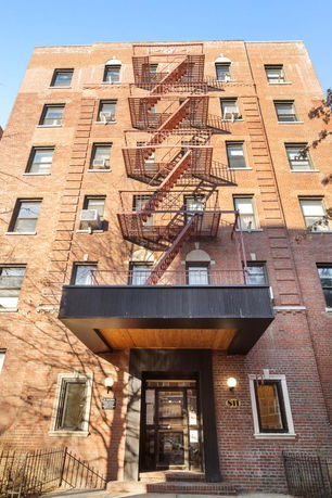 Front view of a multi-story brick building with external fire escapes.