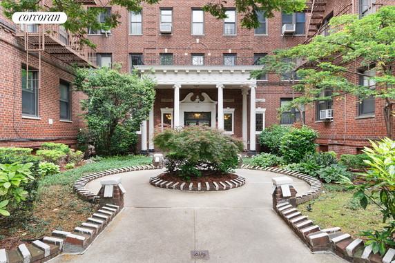 Front view of a brick multi-story building with a landscaped entrance.