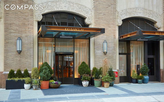 Front view of a building entrance with glass doors and potted plants.