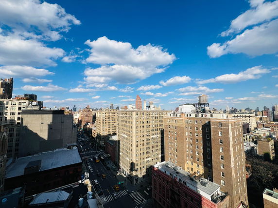 Panoramic view of a cityscape with several tall buildings under a blue sky with clouds.