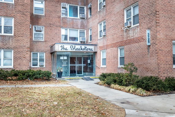 Front view of a multi-story brick building with a glass entrance and signage.