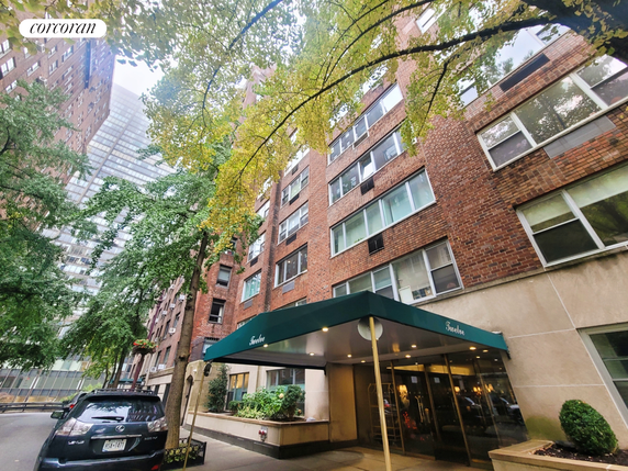Front view of a multi-story brick building with large windows and a green awning entrance.