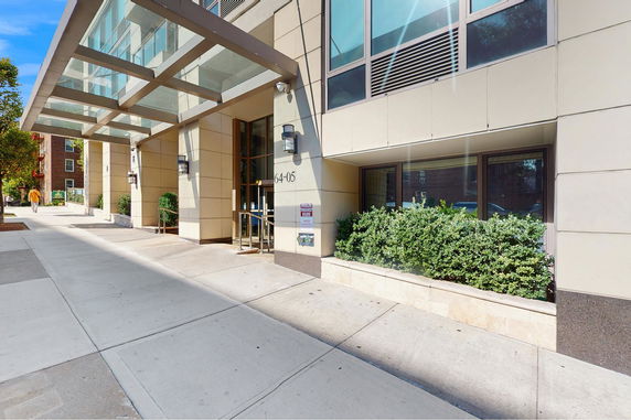Front view of a modern building with glass paneling and a canopy.