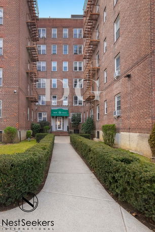 Front view of a multi-story brick apartment building with fire escapes.