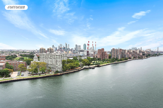 Skyline view of buildings along a river with cityscape in the background.