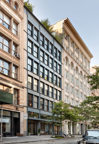 Street view of multi-story buildings with large windows and a modern facade.
