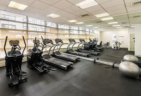 Indoor gym with exercise equipment including treadmills and fitness balls.