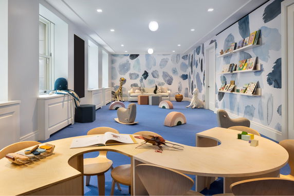 Children's play area with tables, chairs, toys, and books.