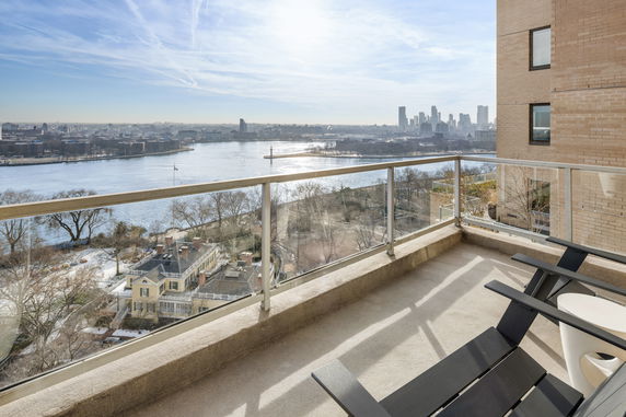 Balcony view overlooking a river and distant city skyline.