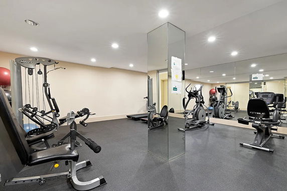 Indoor gym area with various exercise equipment and mirrored walls.