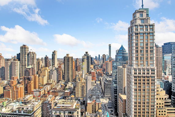 Aerial view of a cityscape with multiple high-rise buildings under a blue sky.