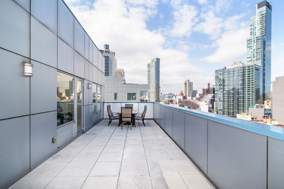 Rooftop with seating area and city skyline in the background.