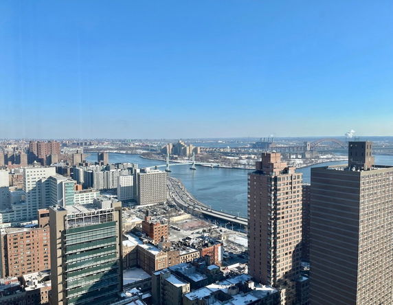 Panoramic view of a cityscape with a river and bridges seen from a high vantage point.