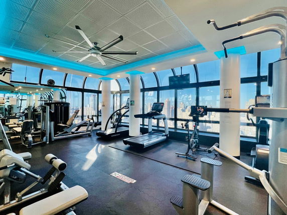 Interior view of a gym with various exercise equipment, including treadmills and weight machines.