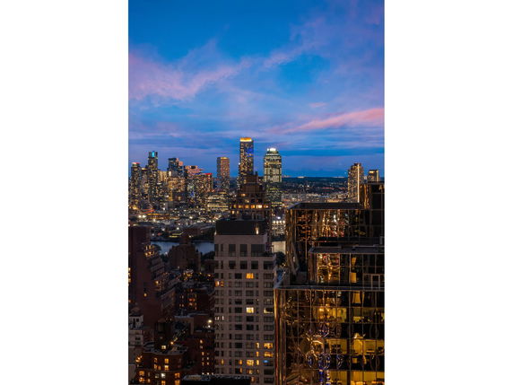 Wide angle view of a cityscape at dusk with illuminated skyscrapers.