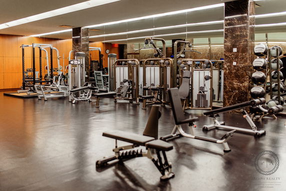 Interior view of a gym with various exercise equipment and mirrored walls.